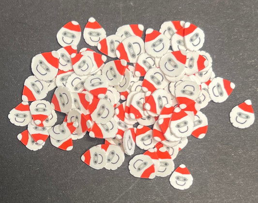 Collection of 5mm Christmas themed polymer clay slices in the shape of Santa or Father Christmas on a dark background