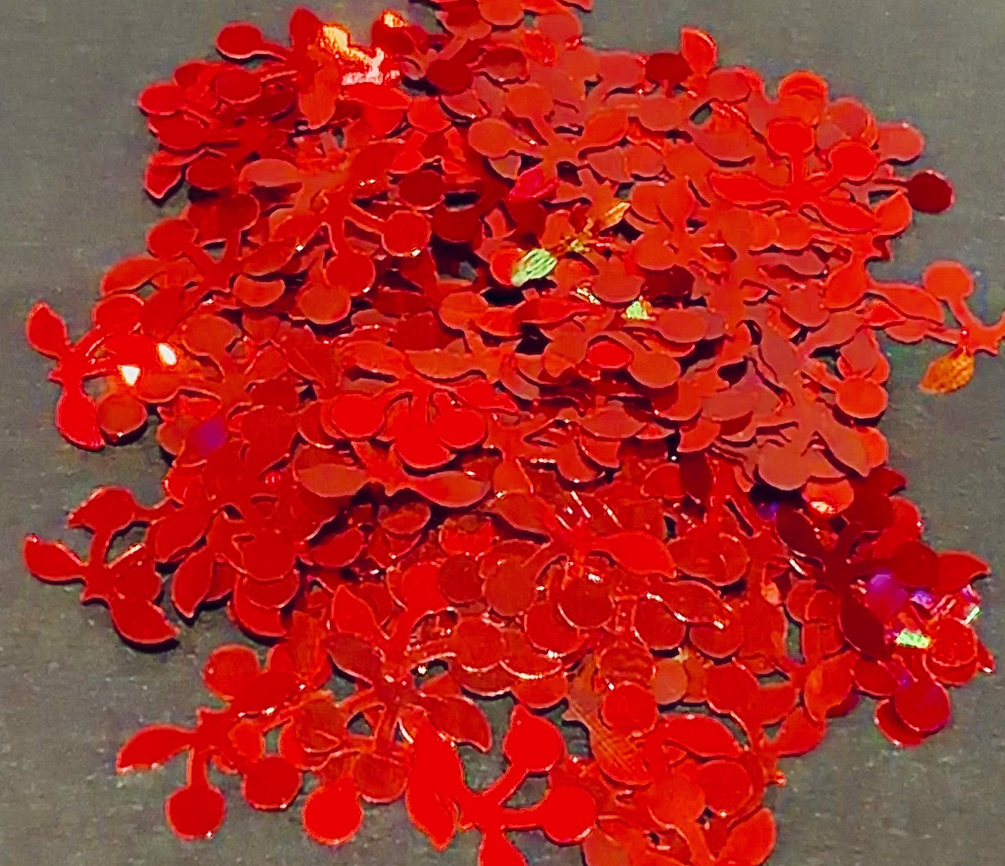 Red cherry glitter shapes confetti falling on a black background